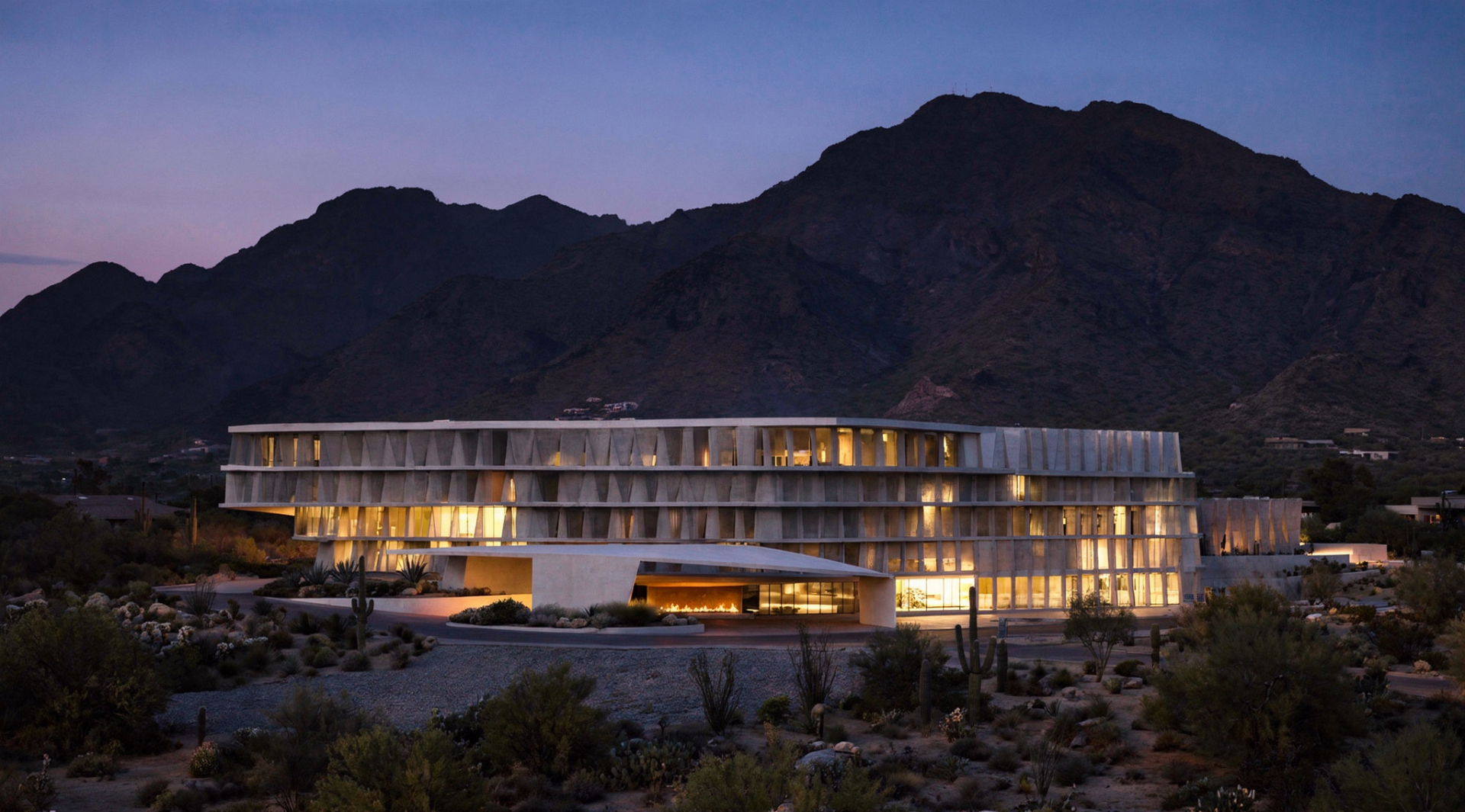 FIRA exterior at dusk — pleated concrete facade illuminated against the Sonoran sky.